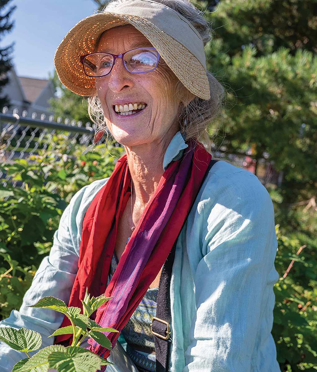 woman wearing wide brimmed hat and scarf holding plant