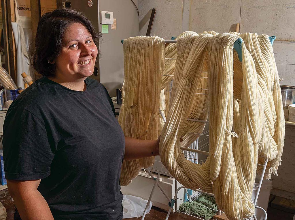 woman smiling in front of rack with skeins of yarn