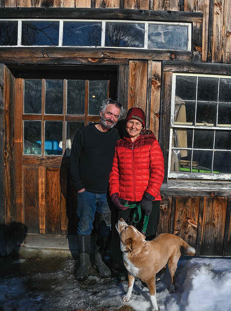 man and woman standing and smiling with dog