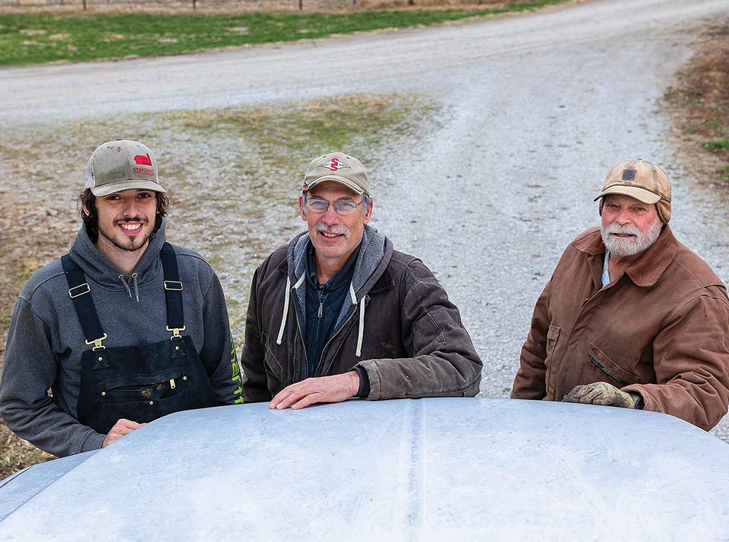 three men leaning on hood of truck