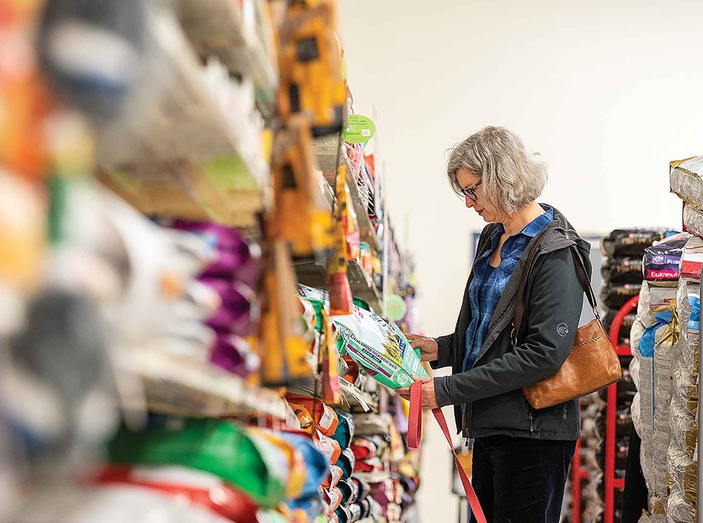 woman looking at dog food in grocery aisle