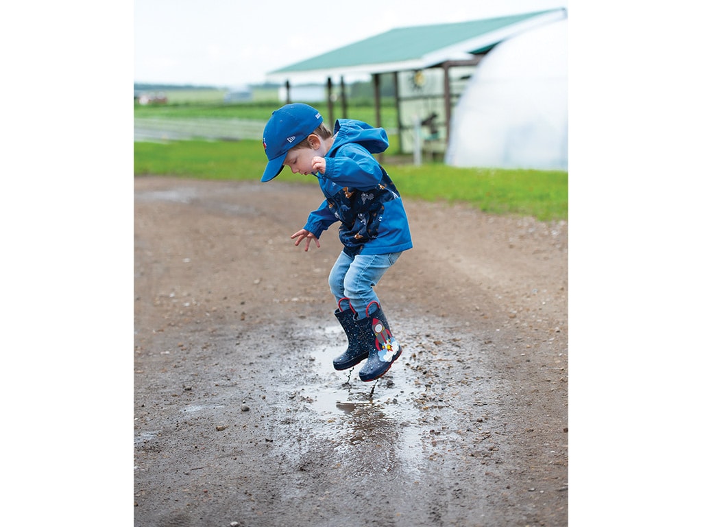 young boy jumping in puddle
