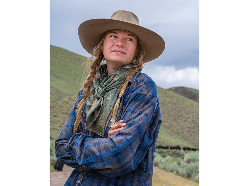 young woman with wide brimmed hat looking out at mountains