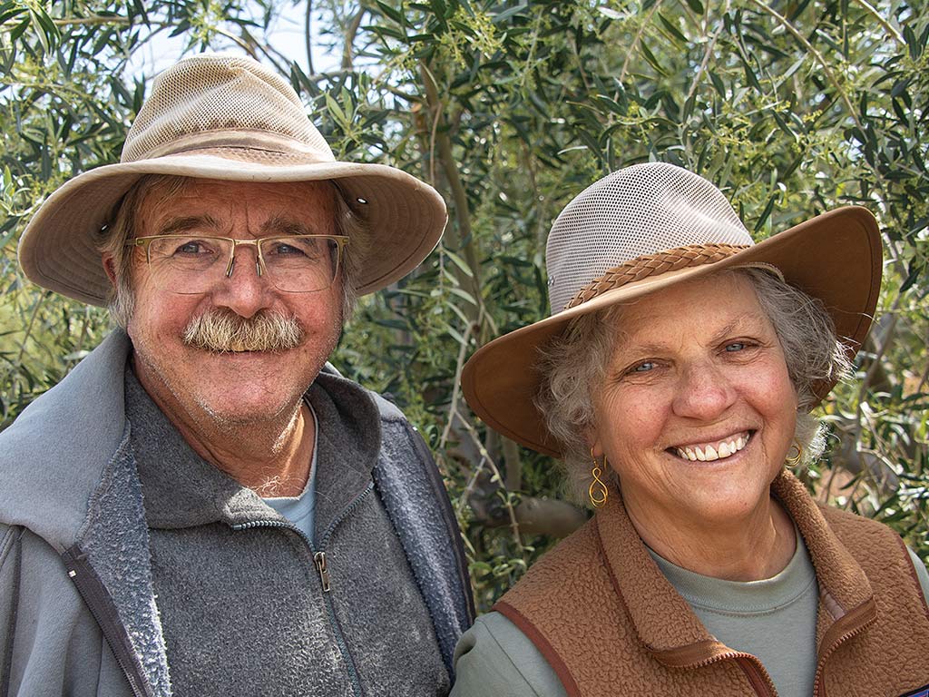 two smiling people with wide-brimmed hats on