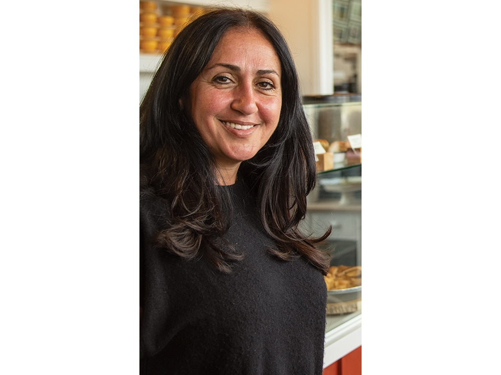 a smiling person in a cafe with dark hair and black sweater