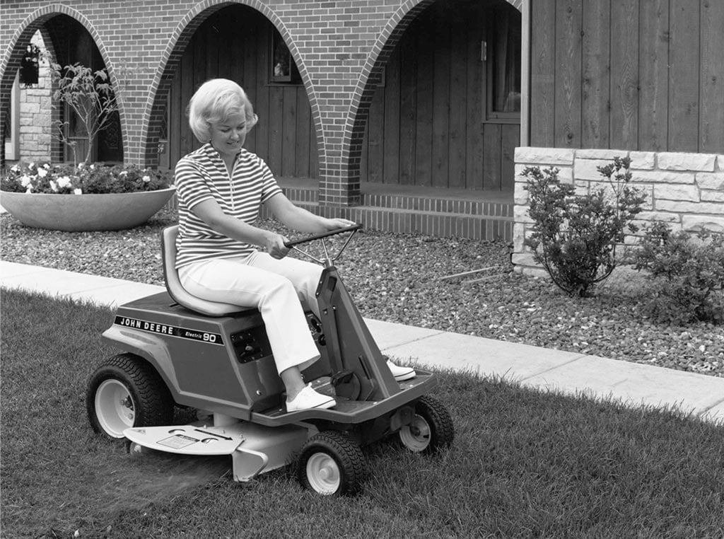 vintage photo of blonde woman driving John Deere residential lawn mower