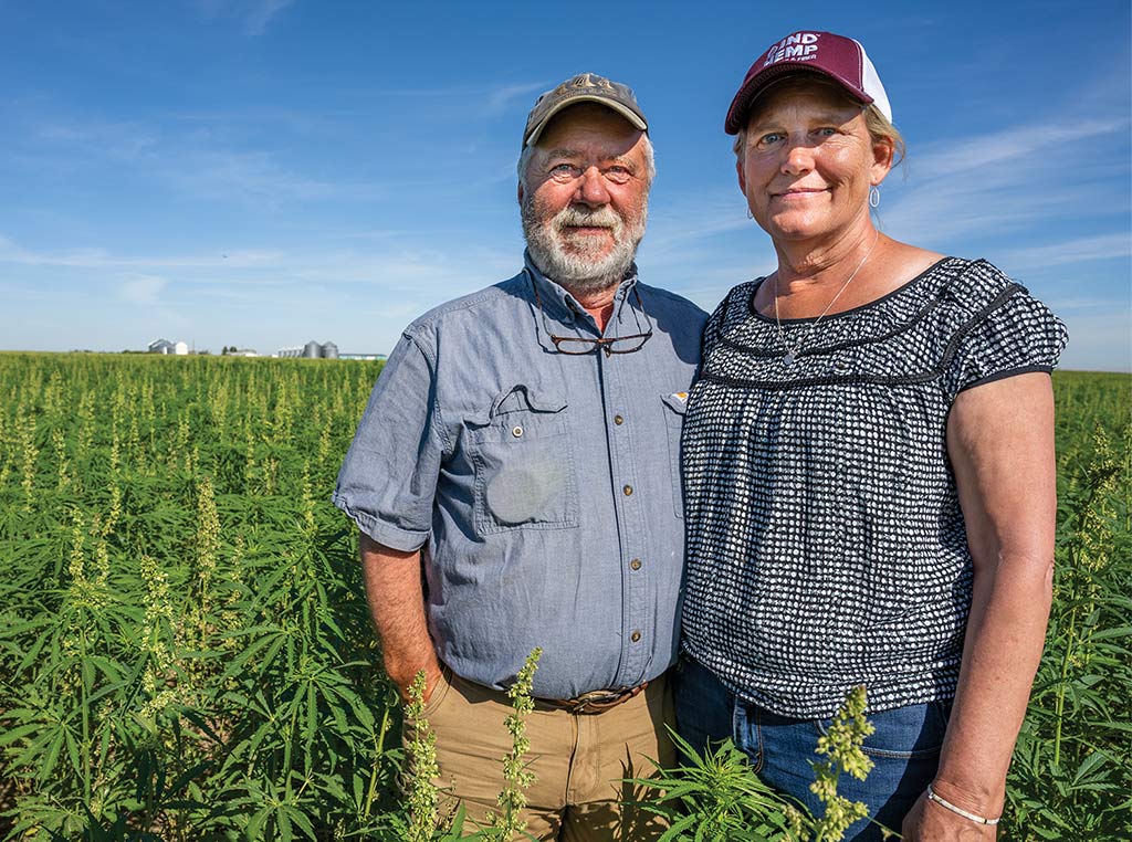 man and woman with baseball caps on smiling in hemp field