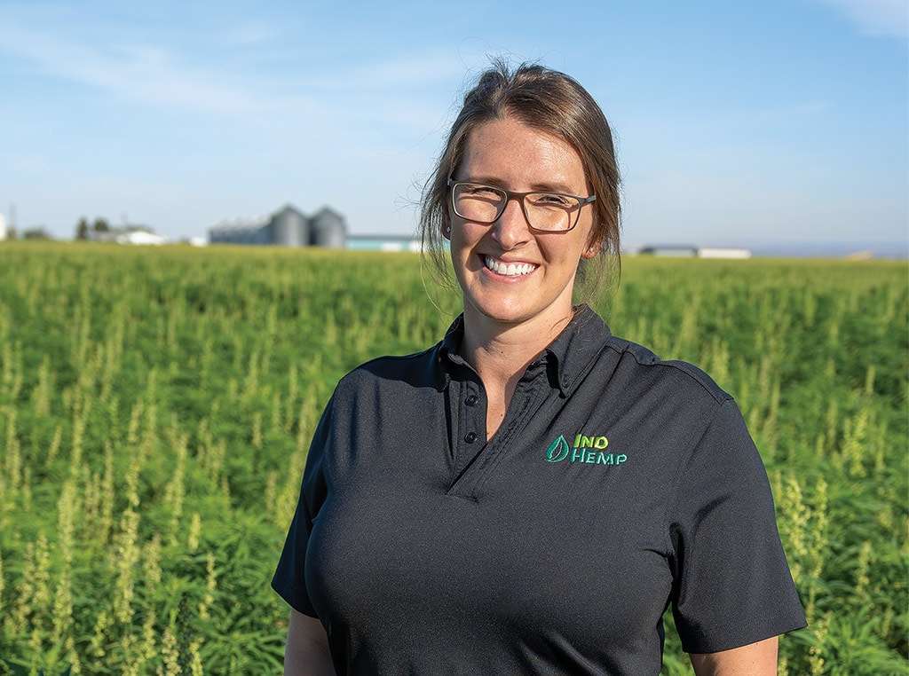 young woman with glasses on standing in hemp field