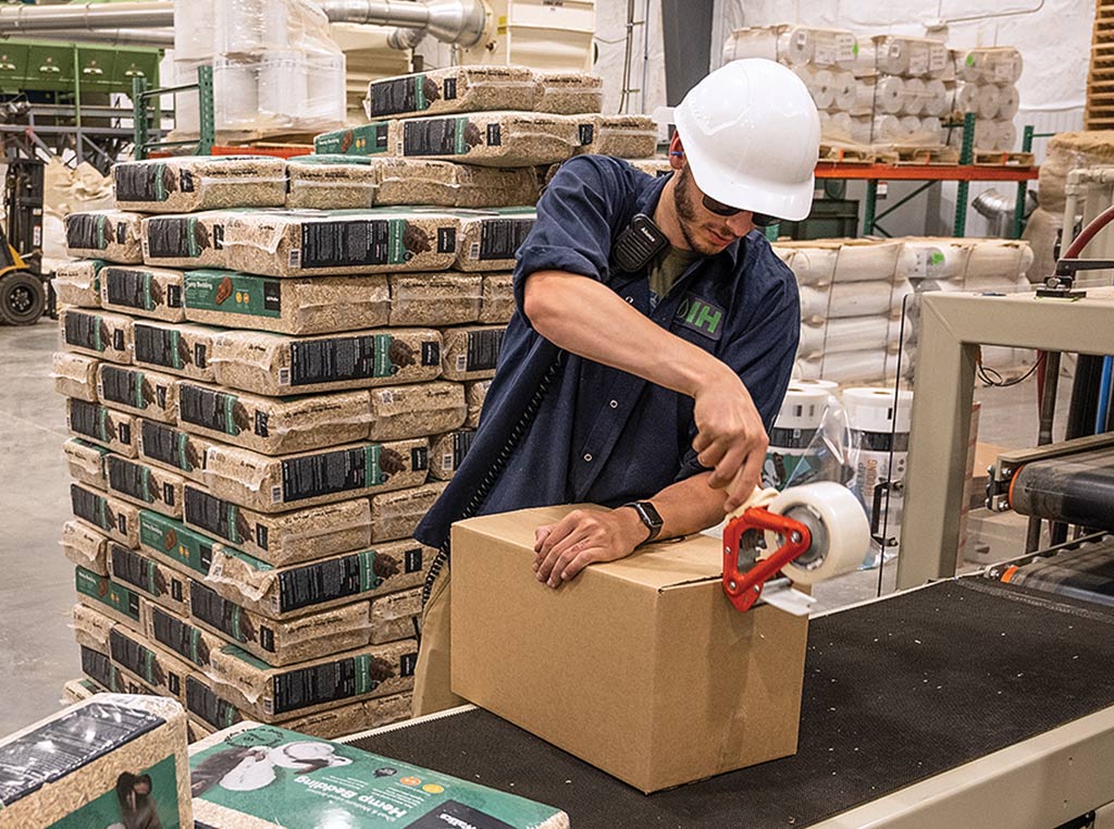 man with hardhat on taping box in warehouse