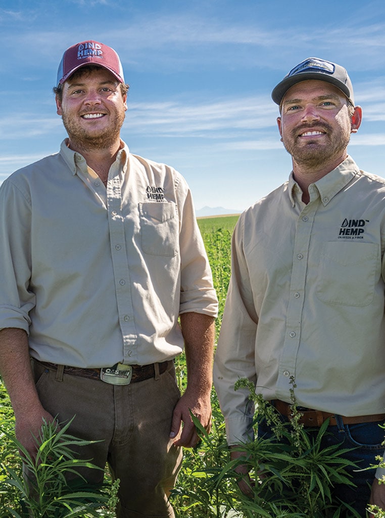 two men with baseball hats on standing in hemp field