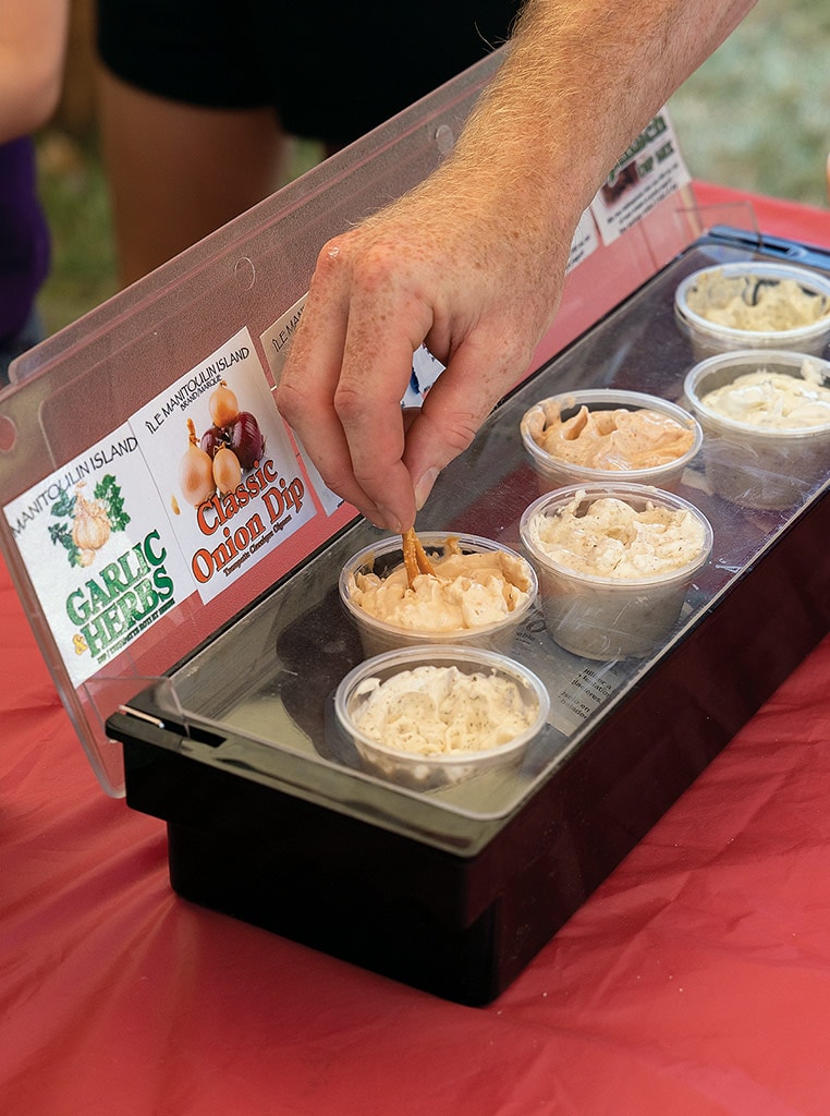 various garlic dips in plastic cups with hand dipping in one