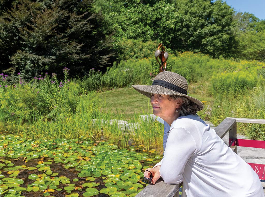 woman with wide brimmed hat looking out at lilypad pond