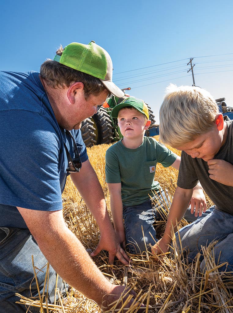 father and two sons kneeling in golden grass