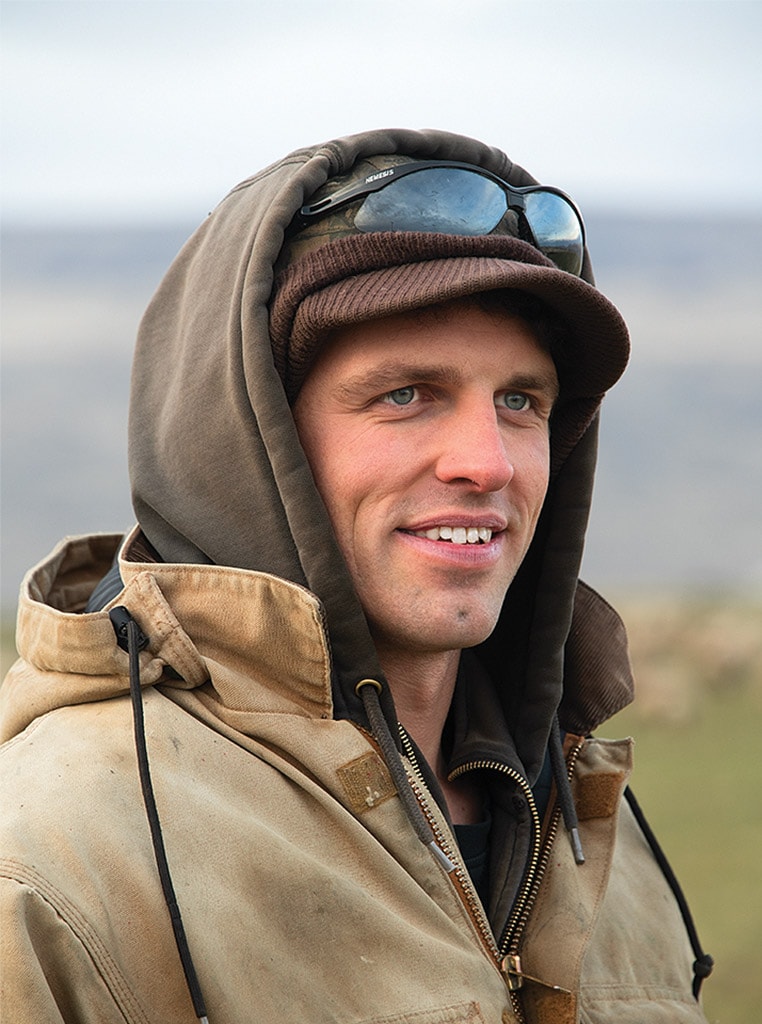 young man with hood and hat smiling