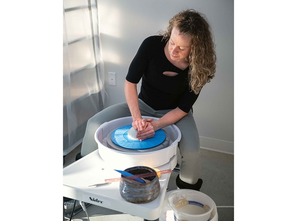 woman modeling clay on pottery wheel