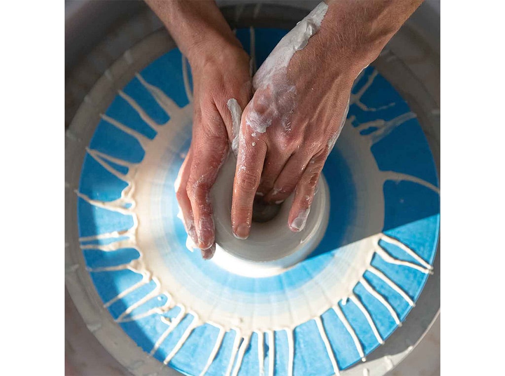 closeup of hands modeling clay on pottery wheel