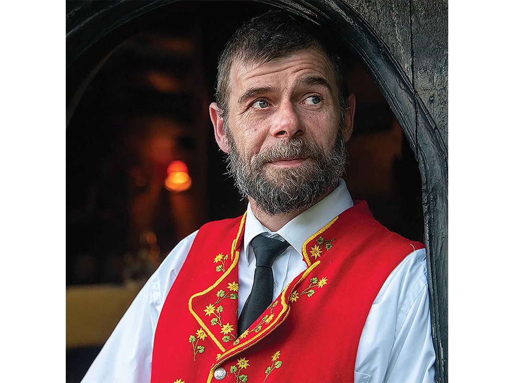 man with beard in red vest and black necktie with white collared shirt