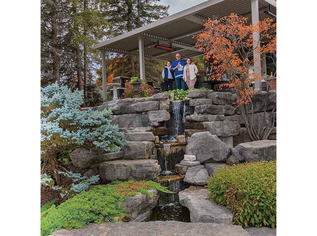 three people standing above landscaped manmade waterfall