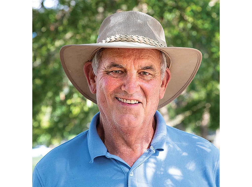 close up to man in light blue polo shirt and tan straw hat