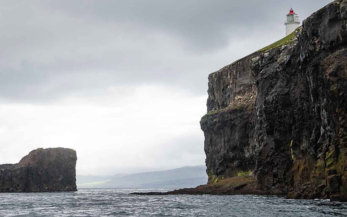 lighthouse on top of cliff surrounded by ocean