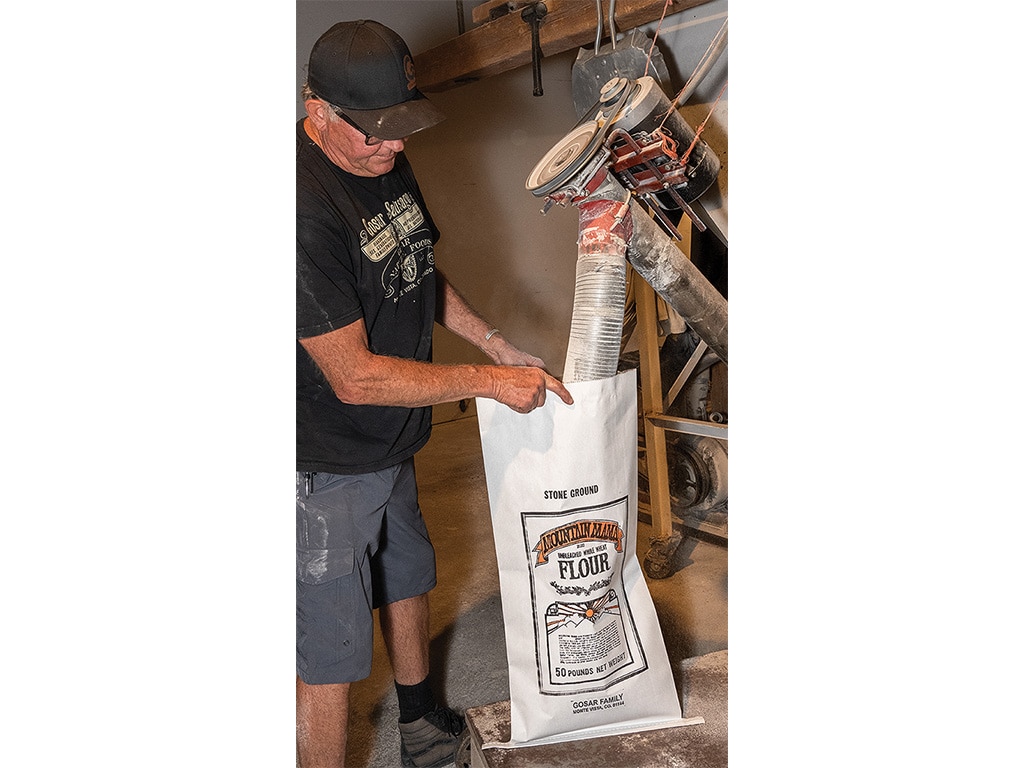 person filling a bag of flour with a machine