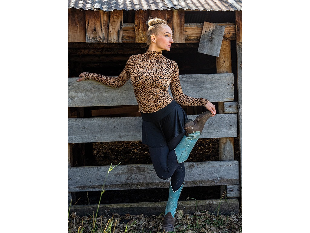 young lady in dancing outfit stretching in front of barn