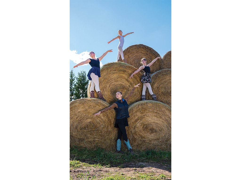 children standing on top of round hay bales posing like dancers