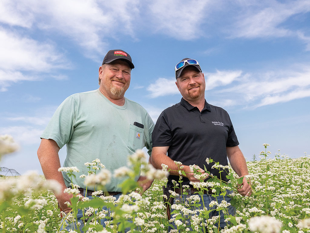 two farmers smiling in field of white flowers