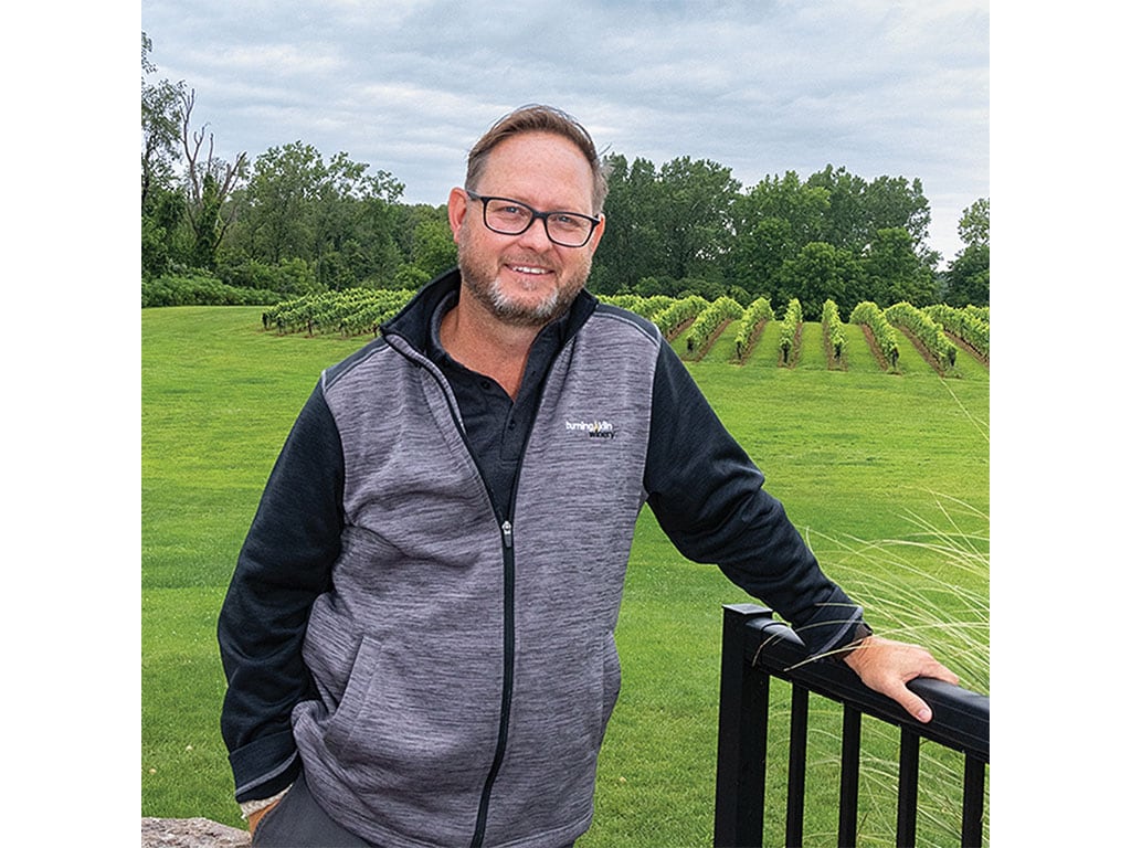 Person smiling outside in front of a garden