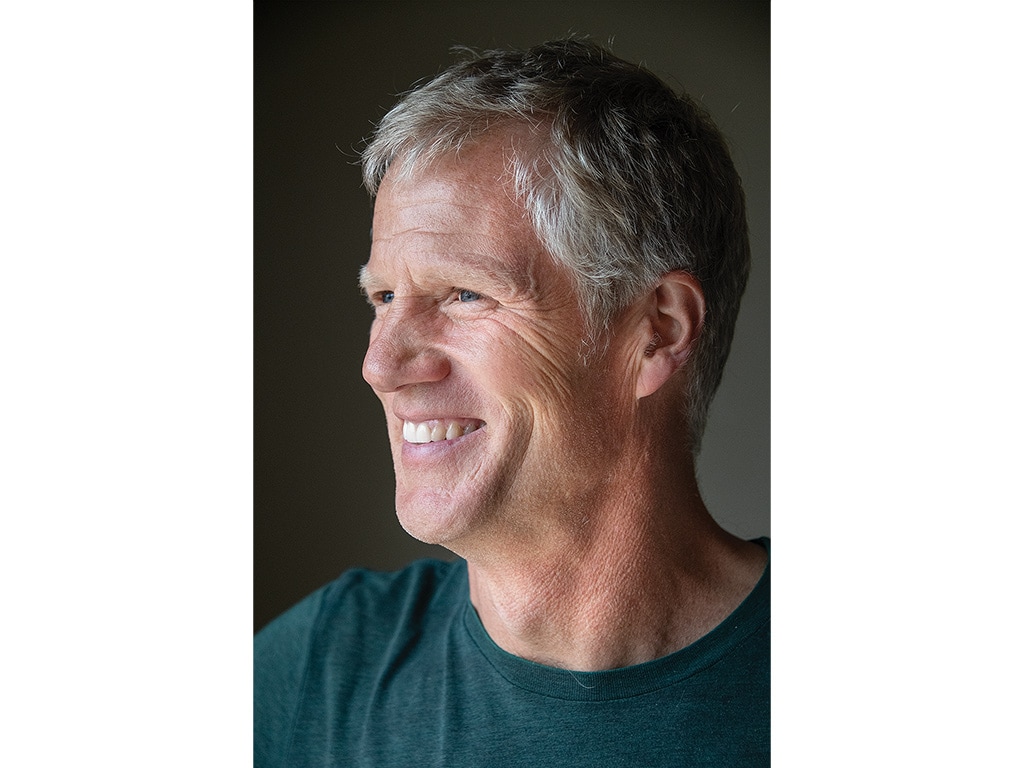 Person smiling in front of a grey wall 