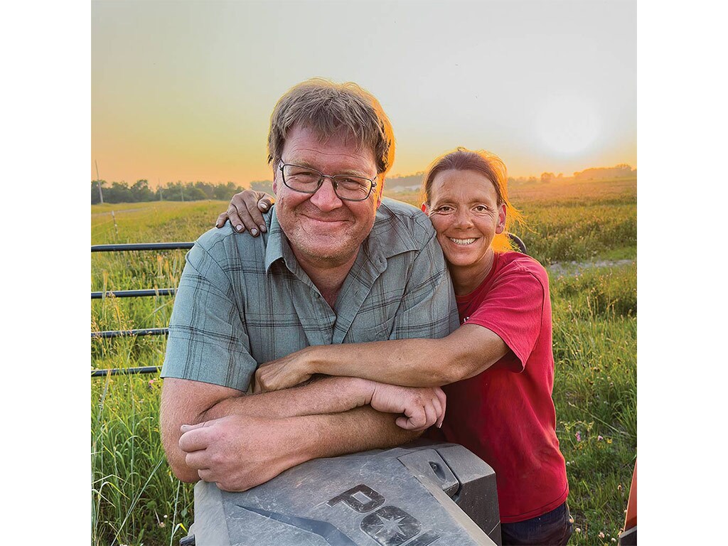 a woman hugging a man with a field behind them