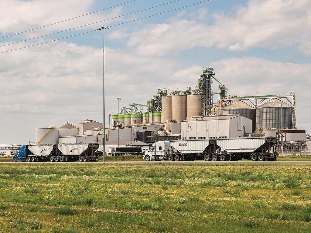 distant picture of two semi trucks parked in front of oil plant