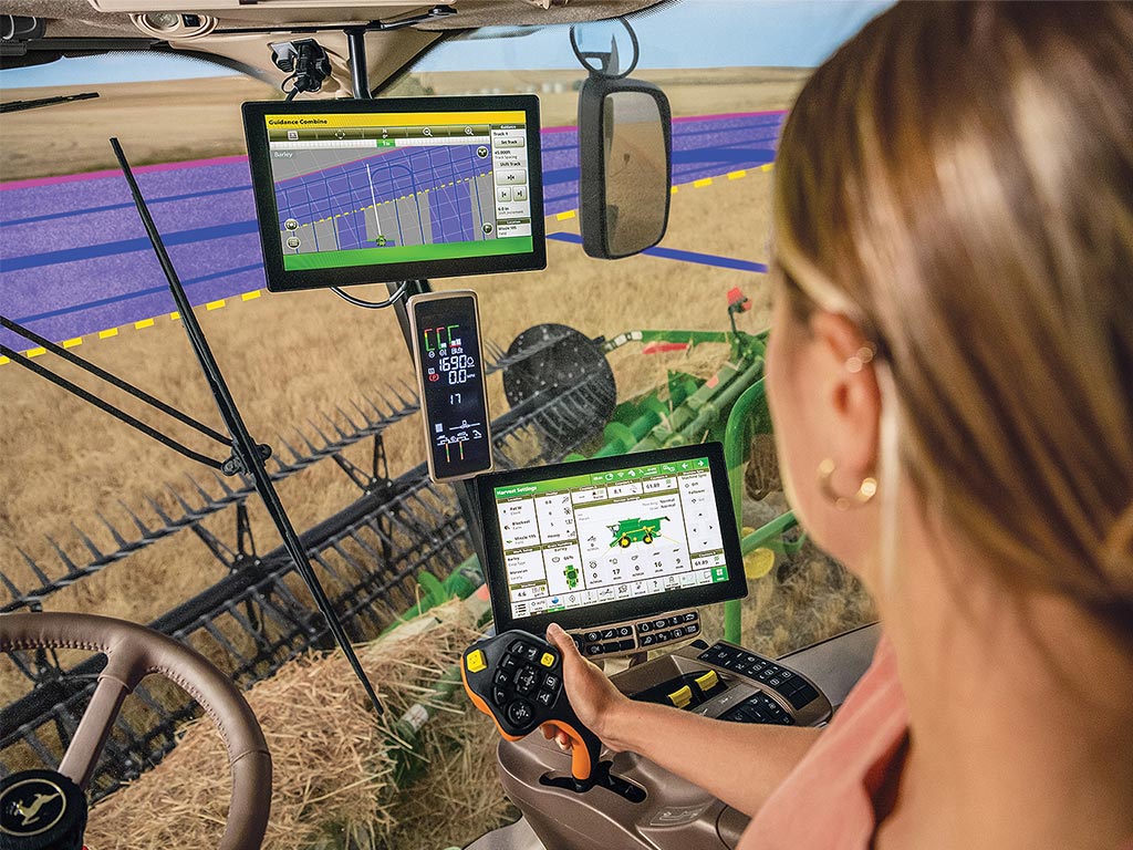 View over farmer’s shoulder in John Deere harvester cab looking at AutoTrac Turn Automation guidance system