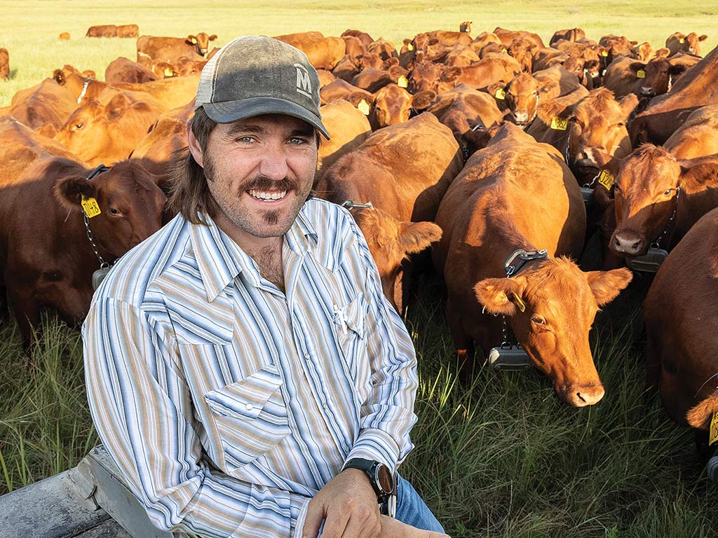 Smiling man standing in front of a herd of cattle