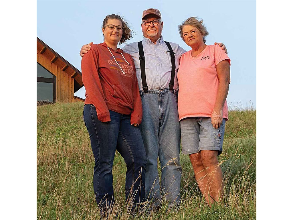 three people standing on a hillside