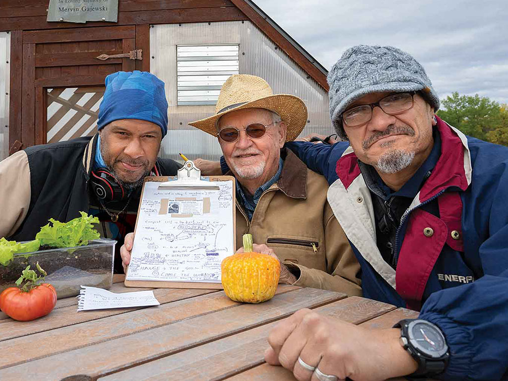 Three smiling farmers at a table with a clipboard
