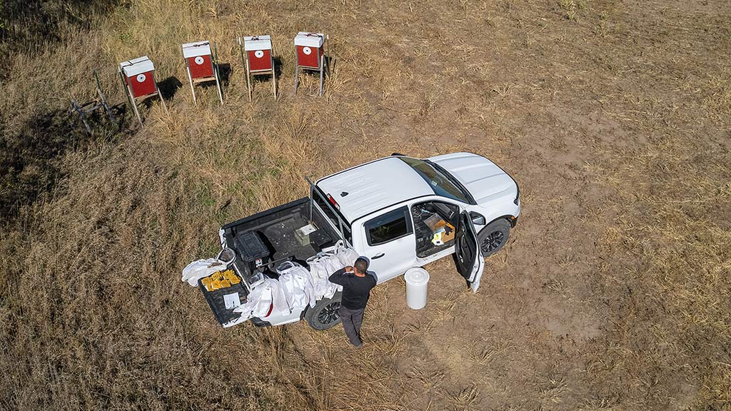 aerial view of white pickup truck with four beehive boxes on one side