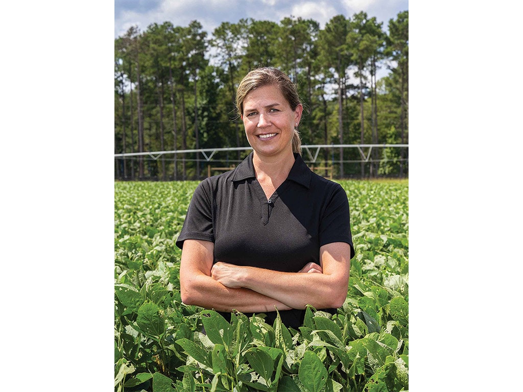 smiling person standing in field with arms crossed