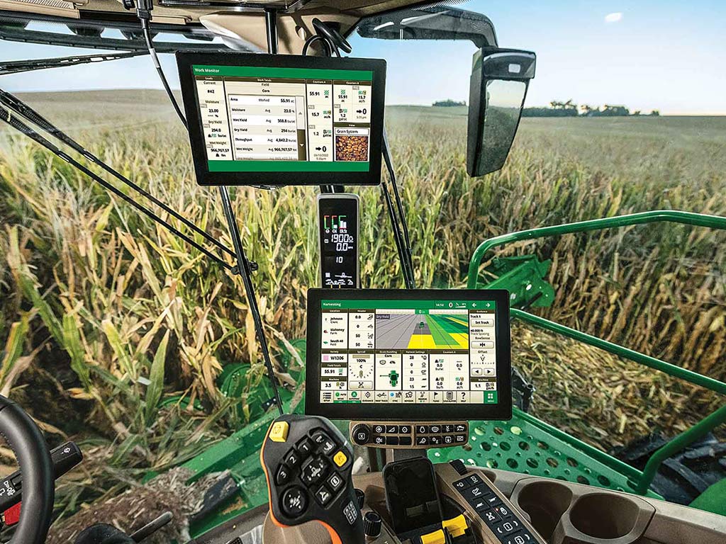 Digital screens and controls inside of a John Deere tractor in a corn field