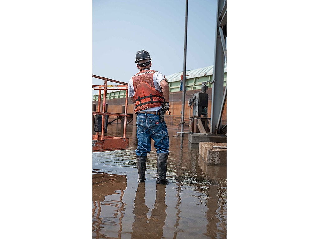 person standing in flood water with high boots and emergency gear on