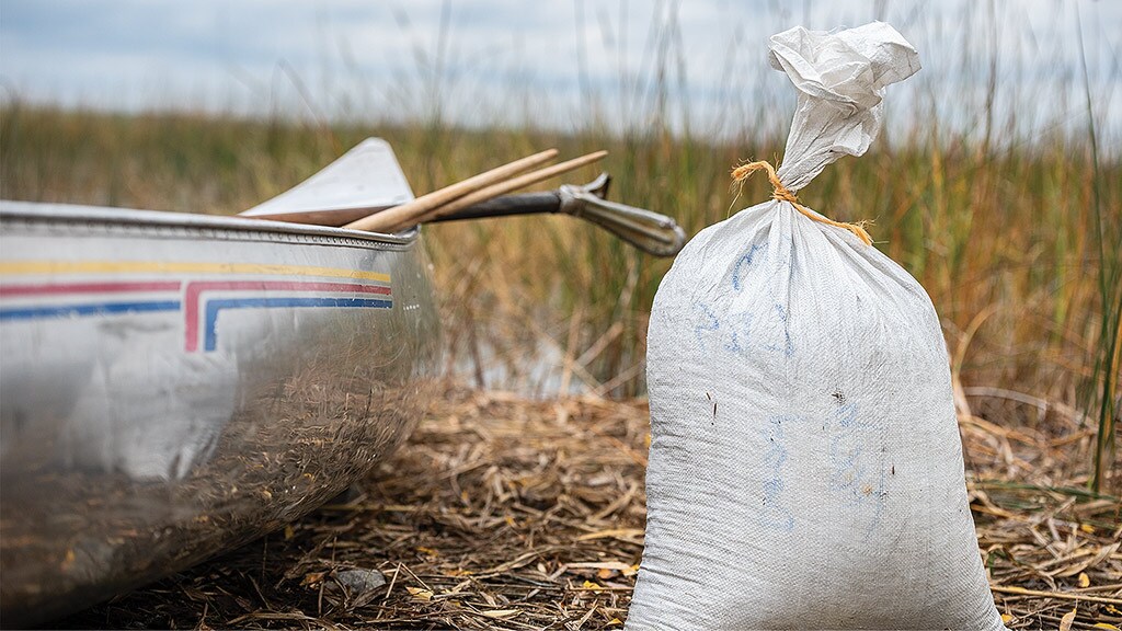 bag tied next to small boat on the banks of lake