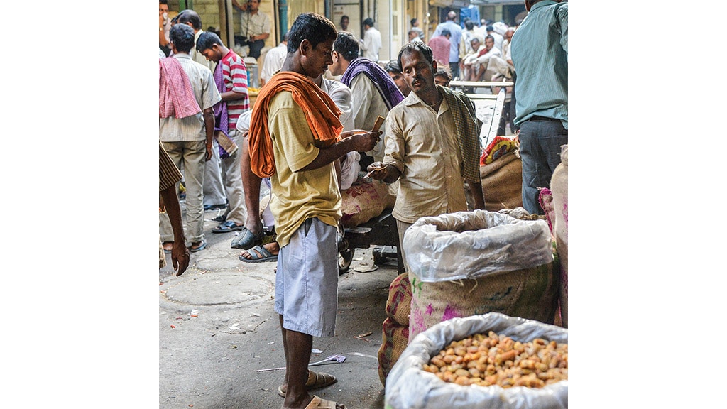 two asian men in the middle of market street collecting moneysurrouding the spices