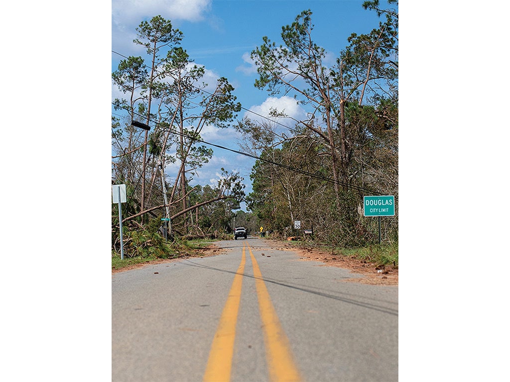 The view from the middle of a road straight down two solid yellow lines with trees on both sides