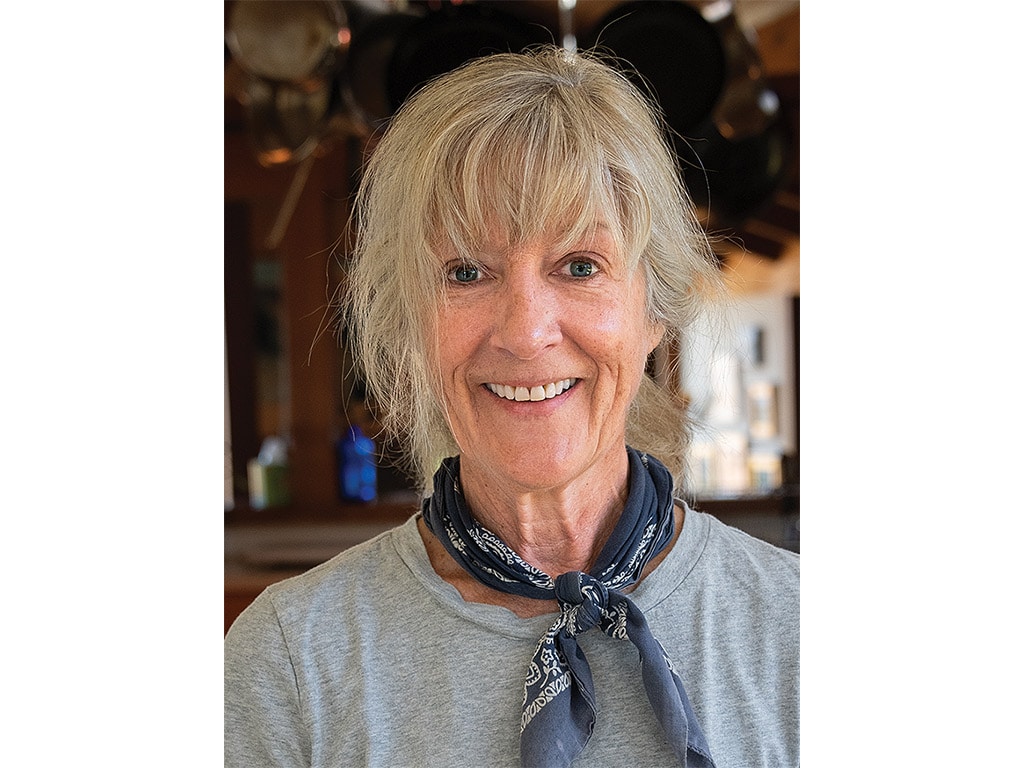 A woman smiling at the camera with a bandana around her neck.