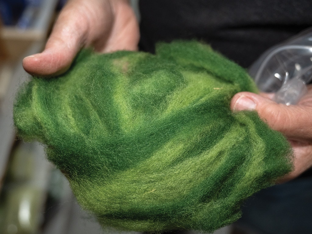 A closeup of hands holding green wool.