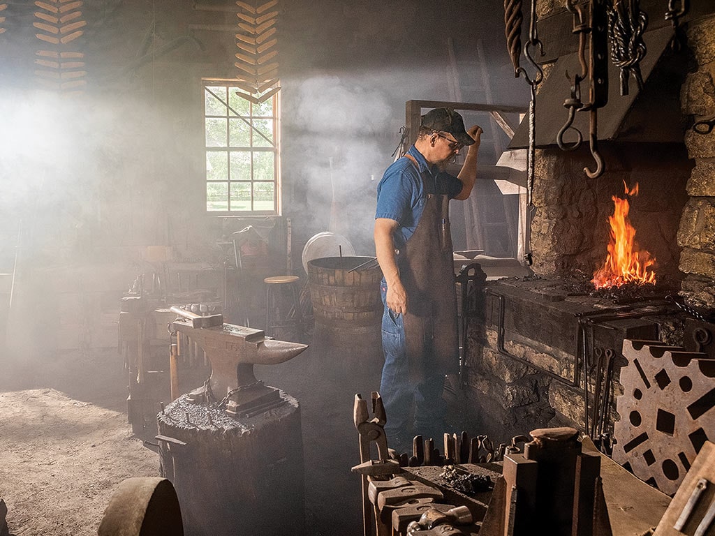 A blacksmith standing over a flaming oven