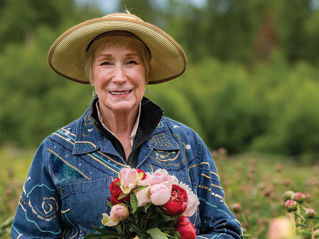 A smiling peony grower holding a bouquet of peonies
