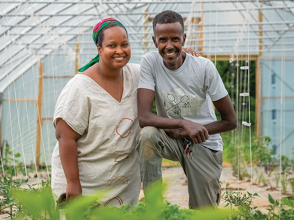 A Somali farming duo smiling in a greehouse