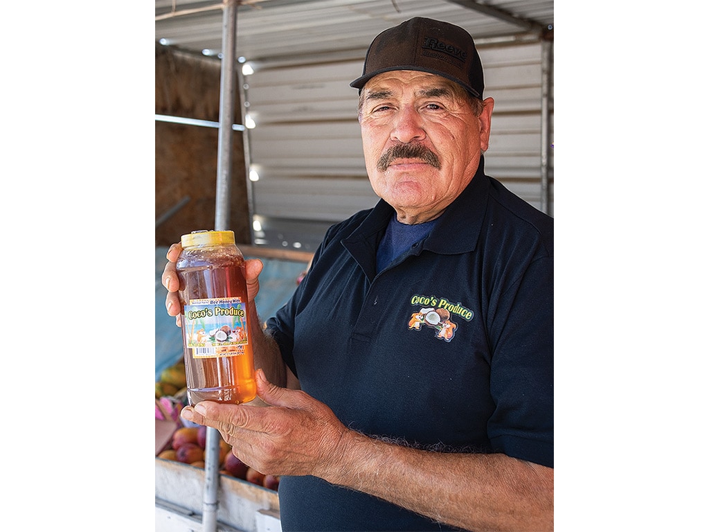 A farmer's market vendor displaying a bottle of honey