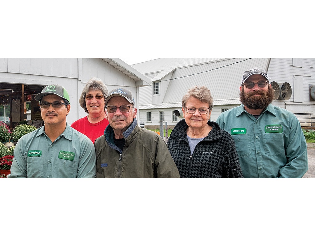 Five people standing in front of the white farmer's market buildings